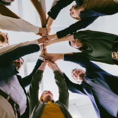 bottom view of united colleagues standing In circle holding hands together - teambuilding in business